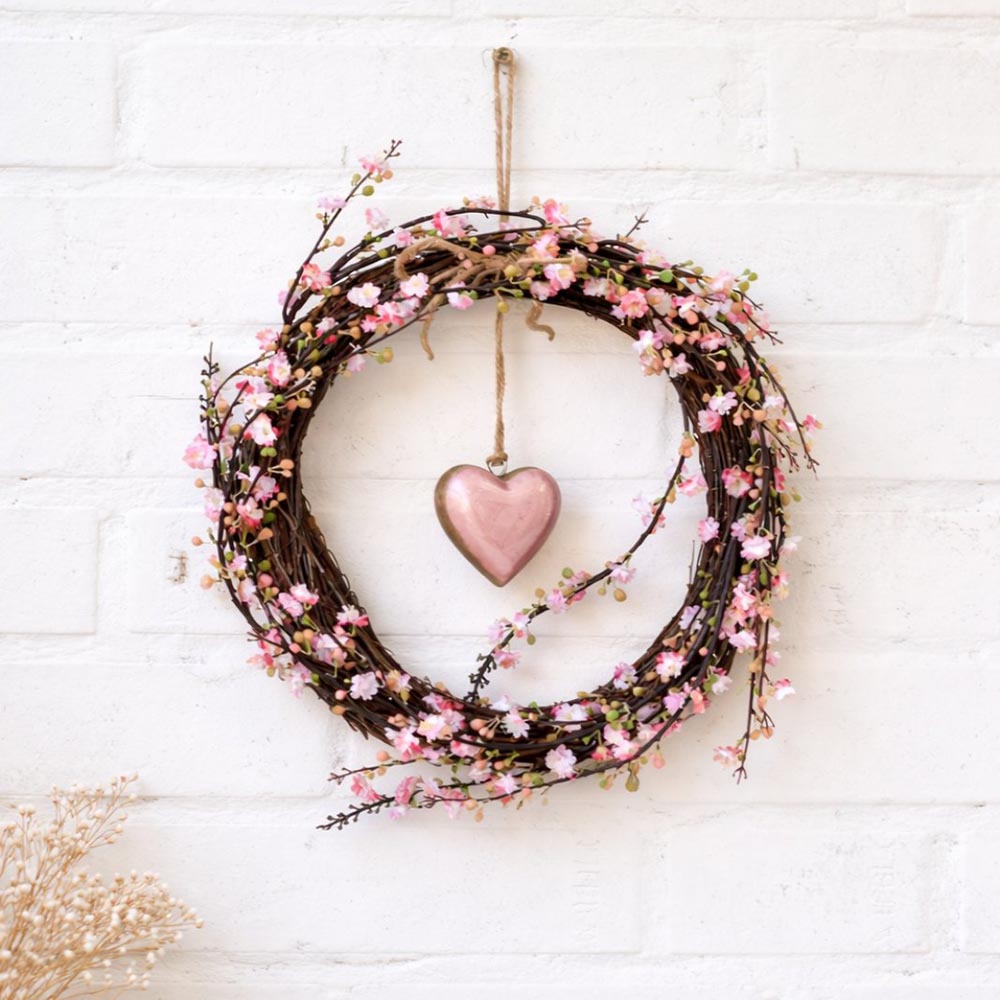 Dekoratív ajtókoszorú rózsaszín virágokkal és szívvel